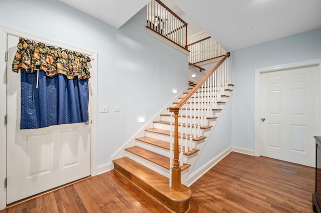 foyer featuring baseboards, stairway, and wood finished floors
