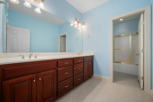 bathroom with baseboards, bath / shower combo with glass door, a sink, double vanity, and tile patterned floors