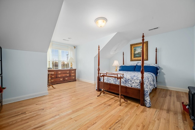 bedroom with light wood-type flooring, baseboards, vaulted ceiling, and visible vents