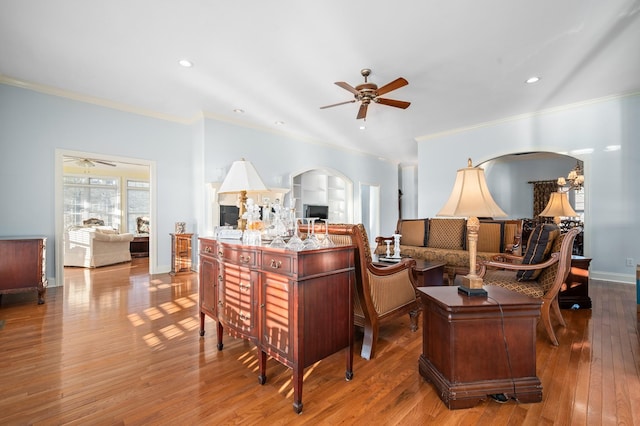 living room with arched walkways, a ceiling fan, hardwood / wood-style flooring, crown molding, and recessed lighting