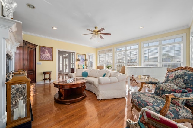 living room with ornamental molding, light wood-style flooring, ceiling fan, and a healthy amount of sunlight