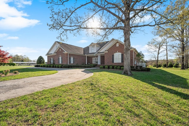 view of front of home with brick siding, driveway, and a front lawn