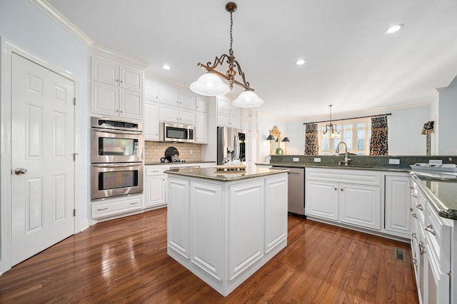 kitchen with dark wood finished floors, white cabinetry, a center island, appliances with stainless steel finishes, and a sink