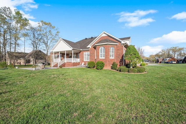 single story home featuring a porch, a front lawn, and brick siding