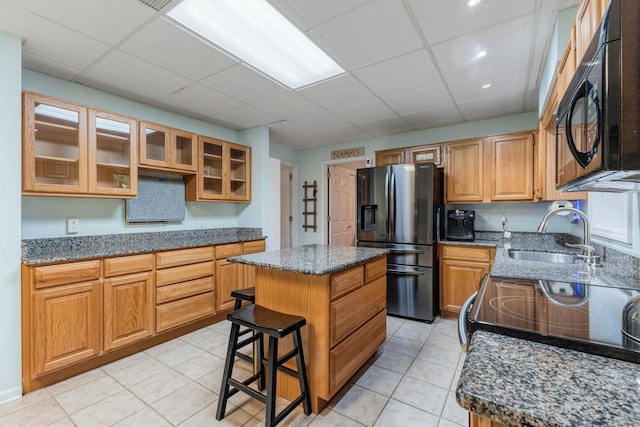7274 Kingston Rd, Fairview, TN 37062 - kitchen with a center island, a sink, dark stone counters, black appliances, and light tile patterned floors