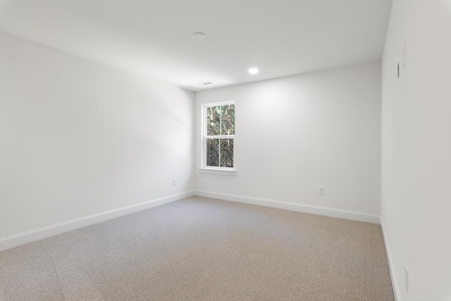spare room with baseboards, recessed lighting, and light colored carpet