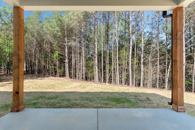 view of yard with a wooded view and a patio