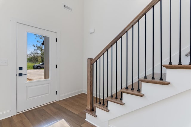 entrance foyer with stairway, visible vents, and wood finished floors