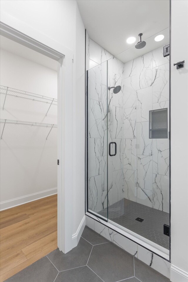 full bathroom featuring baseboards, tile patterned floors, recessed lighting, a marble finish shower, and a walk in closet