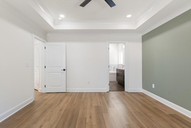 unfurnished bedroom featuring light wood-type flooring, baseboards, ornamental molding, and a raised ceiling