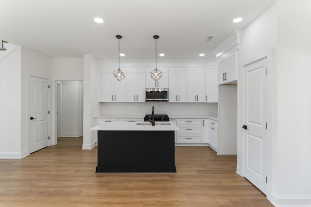 kitchen with light wood-style flooring, light countertops, stainless steel microwave, and backsplash