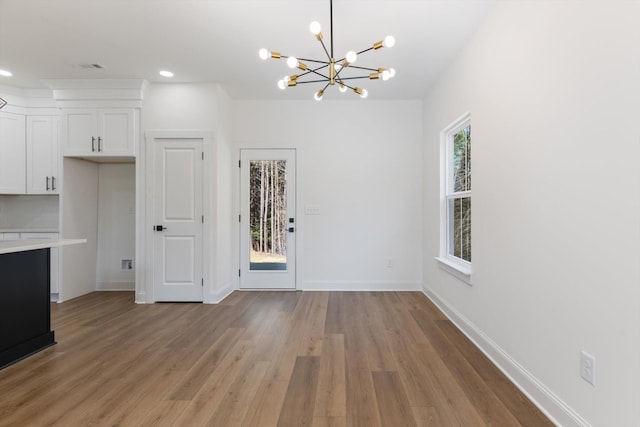 unfurnished dining area with baseboards, an inviting chandelier, recessed lighting, visible vents, and light wood finished floors