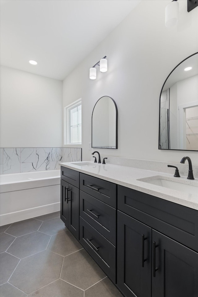 bathroom featuring a sink, double vanity, and a garden tub