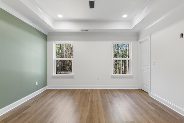 spare room with a raised ceiling, visible vents, and plenty of natural light