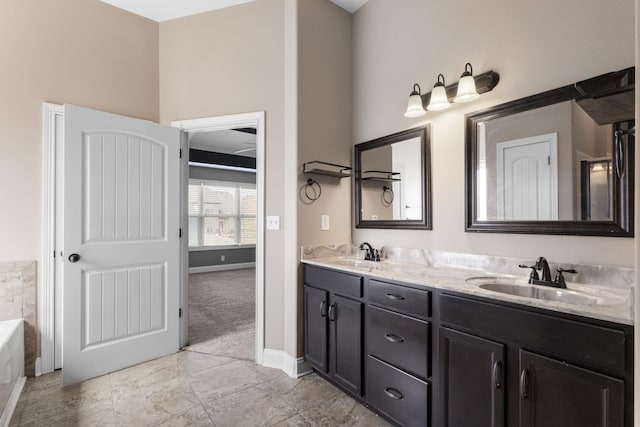 full bath with a sink, baseboards, double vanity, and a tub