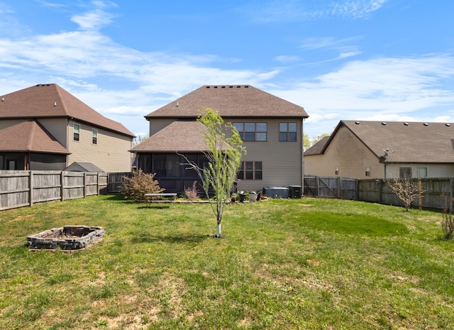 back of house featuring a yard, a fire pit, and a fenced backyard