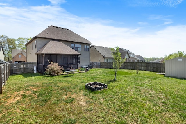 back of house featuring a fenced backyard, a fire pit, a sunroom, and a shed