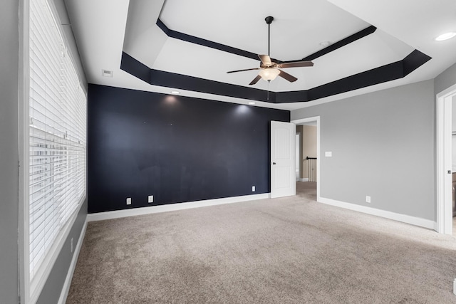 unfurnished bedroom featuring a tray ceiling, ceiling fan, carpet flooring, and baseboards