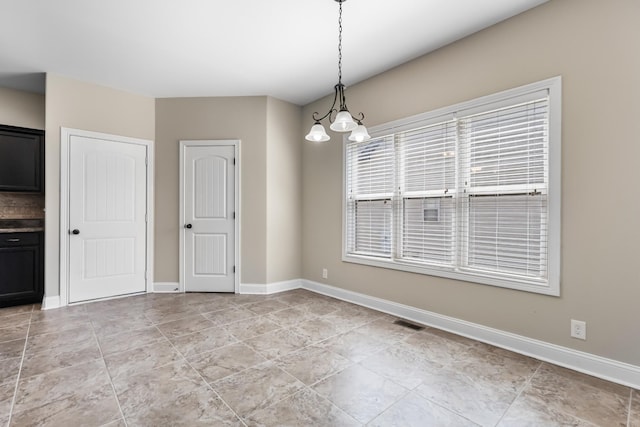 unfurnished dining area featuring visible vents, baseboards, and an inviting chandelier