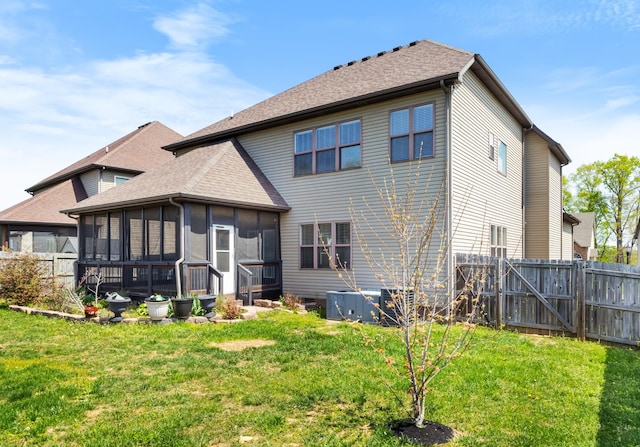 back of house featuring a sunroom, a yard, fence, and a gate