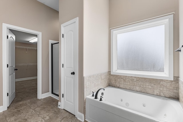 full bath with a shower stall, a walk in closet, a jetted tub, and baseboards