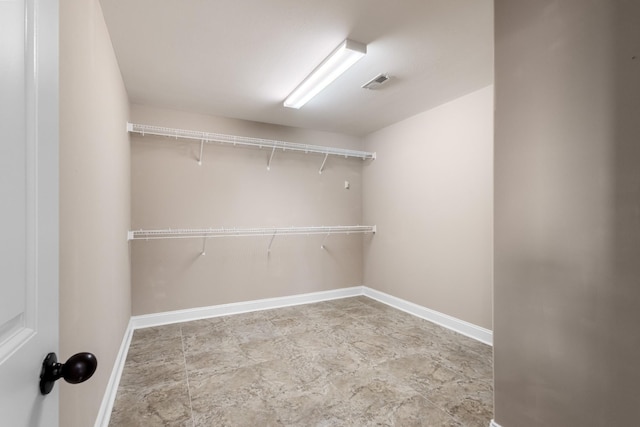 walk in closet featuring stone finish flooring and visible vents