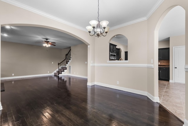 unfurnished dining area with ceiling fan with notable chandelier, ornamental molding, stairway, wood finished floors, and baseboards