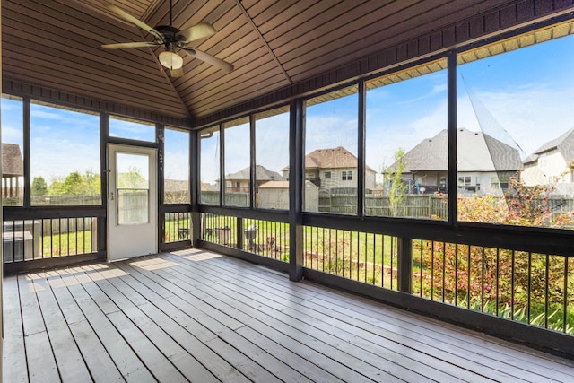 unfurnished sunroom featuring ceiling fan and a residential view