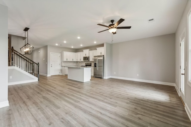 560 Twyla Dr, Lebanon, TN 37087 - unfurnished living room with recessed lighting, light wood-style floors, ceiling fan, stairs, and a chandelier