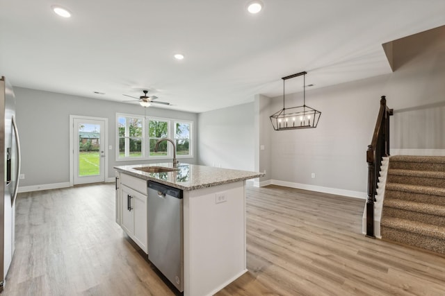 560 Twyla Dr, Lebanon, TN 37087 - kitchen featuring appliances with stainless steel finishes, light stone counters, light wood-style flooring, white cabinetry, and an island with sink