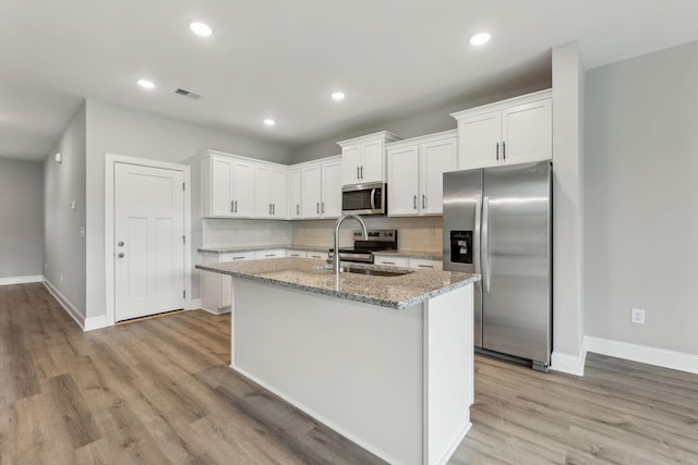 560 Twyla Dr, Lebanon, TN 37087 - kitchen featuring appliances with stainless steel finishes, backsplash, an island with sink, light wood-style floors, and recessed lighting