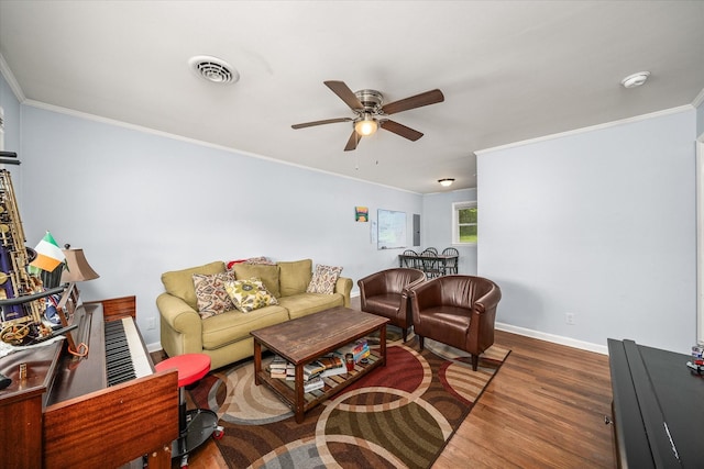 living area with wood finished floors, visible vents, ornamental molding, baseboards, and ceiling fan