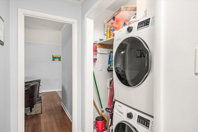 laundry room with baseboards, wood finished floors, stacked washing maching and dryer, and laundry area