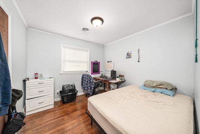 bedroom featuring baseboards, ornamental molding, wood finished floors, and visible vents