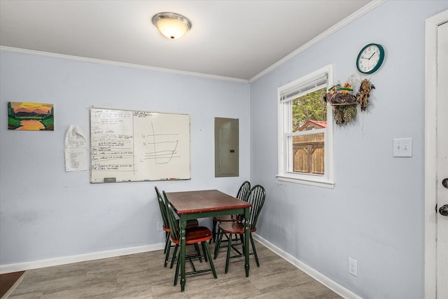 dining area with baseboards, ornamental molding, wood finished floors, and electric panel