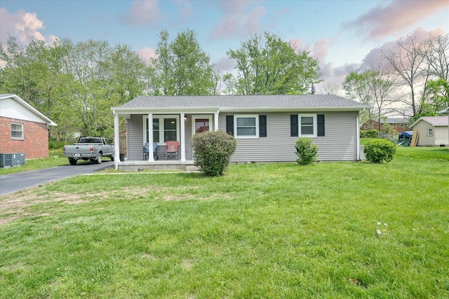 ranch-style home with central AC unit, driveway, a porch, and a front lawn