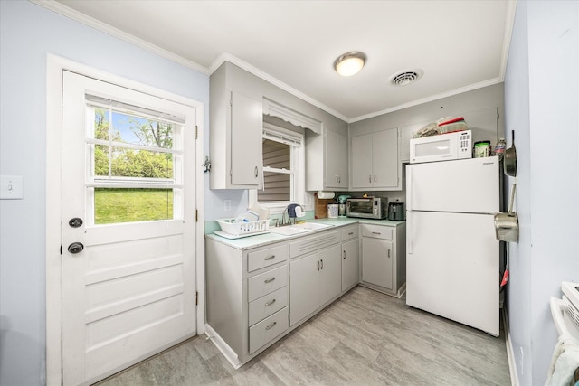 kitchen with a sink, white appliances, light countertops, ornamental molding, and visible vents