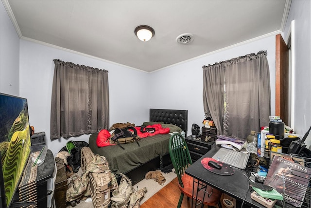 bedroom with wood finished floors, visible vents, and ornamental molding