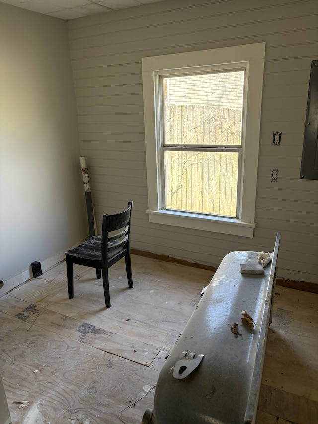miscellaneous room with electric panel, wooden walls, and baseboards
