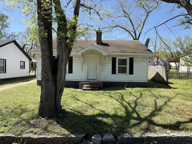 exterior space with a front yard, fence, and a chimney