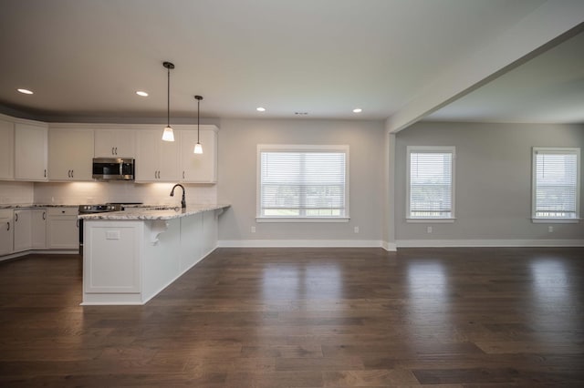 4302 Peacemill Ln, Murfreesboro, TN 37128 - kitchen with stainless steel microwave, a peninsula, white cabinetry, light stone countertops, and tasteful backsplash