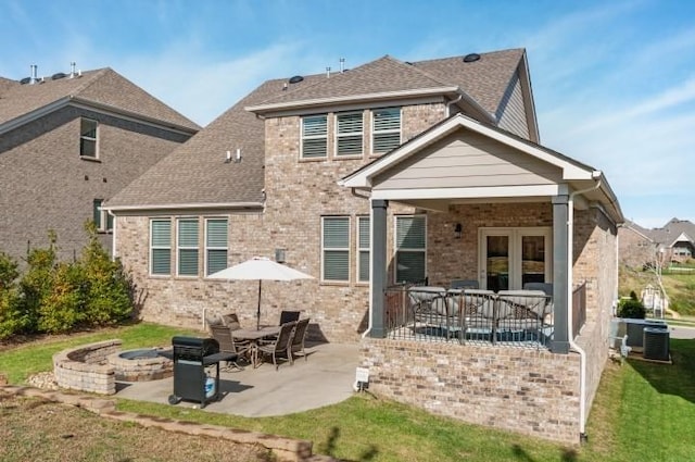 back of property featuring brick siding, a fire pit, a patio, and roof with shingles