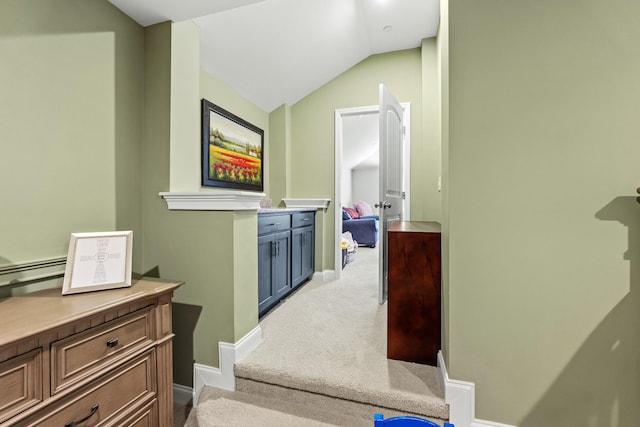 hall with baseboards, vaulted ceiling, and light carpet