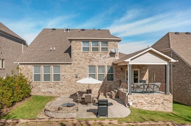 rear view of property featuring a patio area, brick siding, a fire pit, and a shingled roof