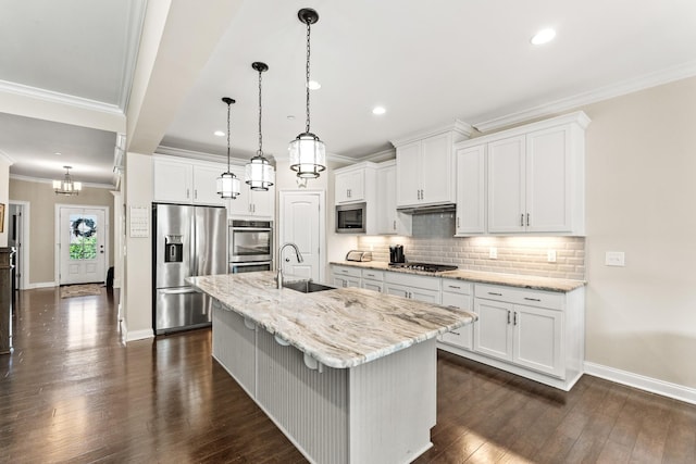 kitchen featuring tasteful backsplash, ornamental molding, white cabinets, appliances with stainless steel finishes, and a sink