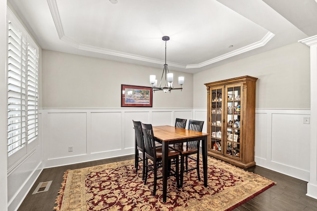 dining area with a tray ceiling, a chandelier, dark wood finished floors, and visible vents
