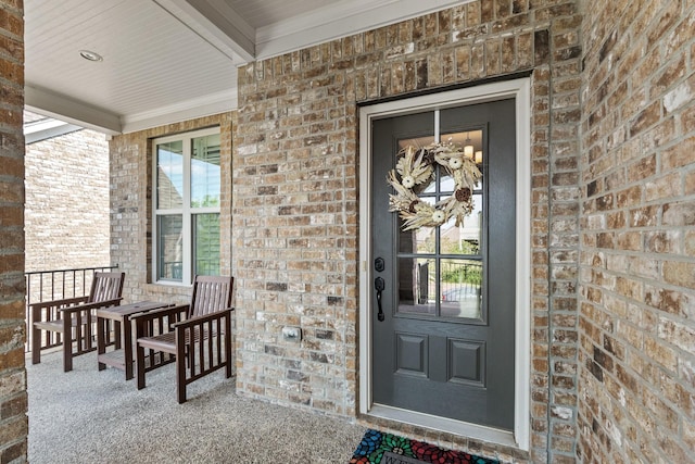 entrance to property featuring brick siding and covered porch