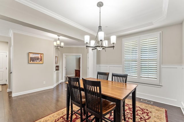dining space featuring an inviting chandelier, crown molding, a wainscoted wall, visible vents, and dark wood finished floors