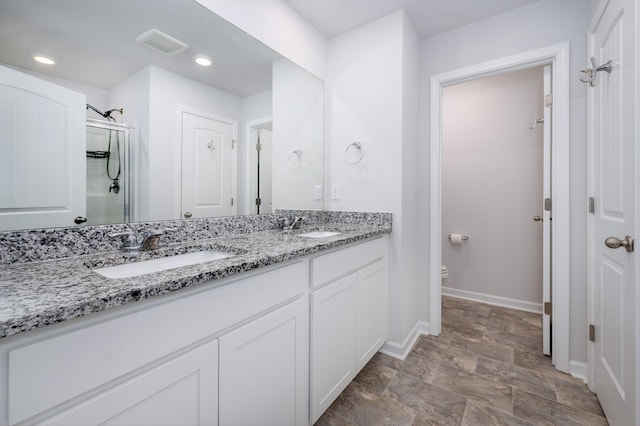 bathroom featuring a sink, visible vents, toilet, and double vanity