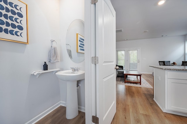 bathroom featuring wood finished floors, a sink, baseboards, and visible vents